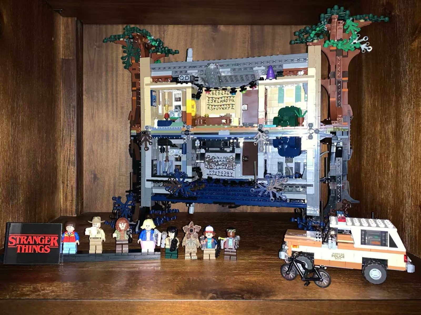 A completed Stranger Things LEGO set, the house mirrored between the everyday world and the Upside Down, with minifigures lined up in front.