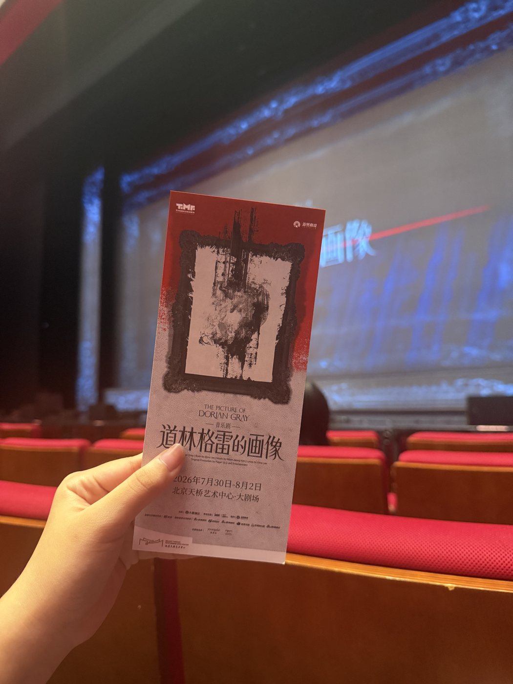 A program for the musical The Picture of Dorian Gray held in a dim Beijing theater, rows of red seats behind.